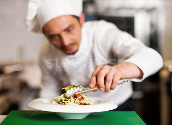 A chef arranging tossed salad in a white bowl Stock photo © stockyimages
