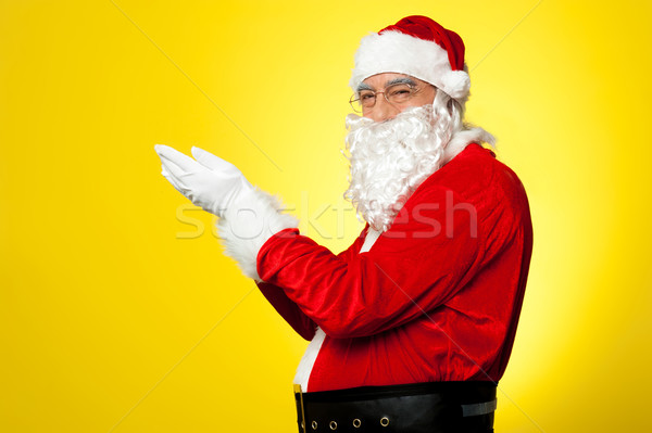 Side profile of Santa facing camera with open palms Stock photo © stockyimages