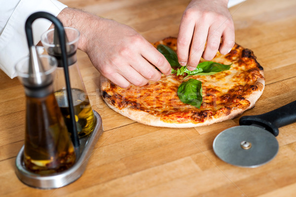 Chef giving finishing touch to pizza in kitchen Stock photo © stockyimages