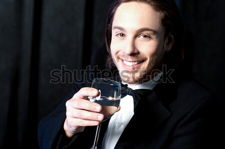 Smiling guy in tuxedo drinking cocktail Stock photo © stockyimages