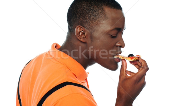 Young man eating a slice of pizza Stock photo © stockyimages