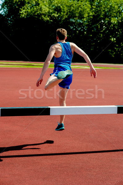 Athlete jumping over the hurdle Stock photo © stockyimages