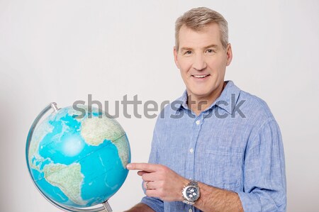 Young cheerful man holding a globe in his hand Stock photo © stockyimages