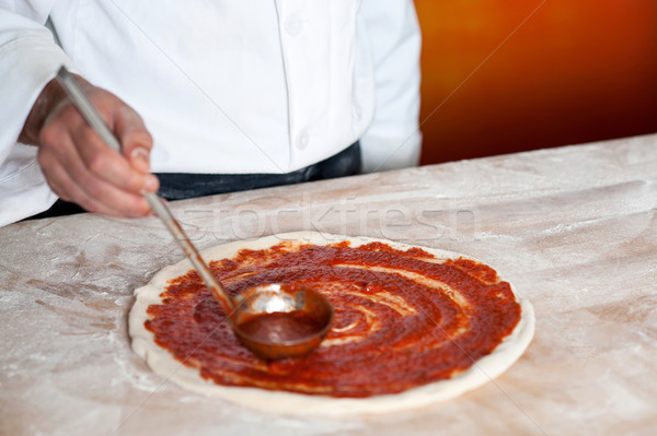 Chef baker spreading sauce on pizza base Stock photo © stockyimages