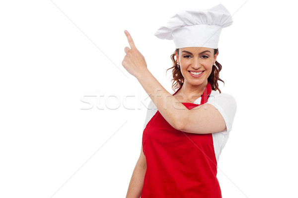 Stock photo: Attractive female chef pointing at copy space