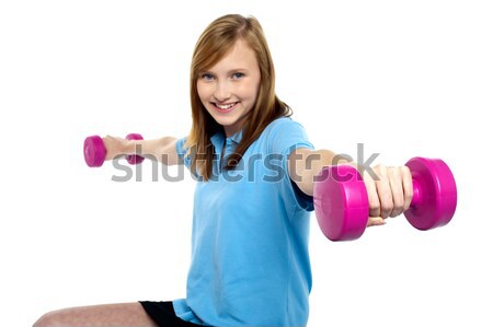 Cute young girl stretching dumbbells sideways Stock photo © stockyimages