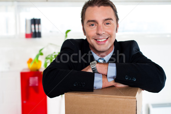 Handsome businessman leaning on packed carton Stock photo © stockyimages