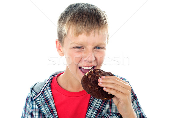 Smart looking young boy relishing yummy chocolate cookie Stock photo © stockyimages