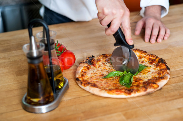 Chef cutting pizza into pieces Stock photo © stockyimages