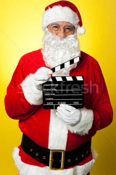 Cheerful Kris Kringle posing with clapperboard Stock photo © stockyimages