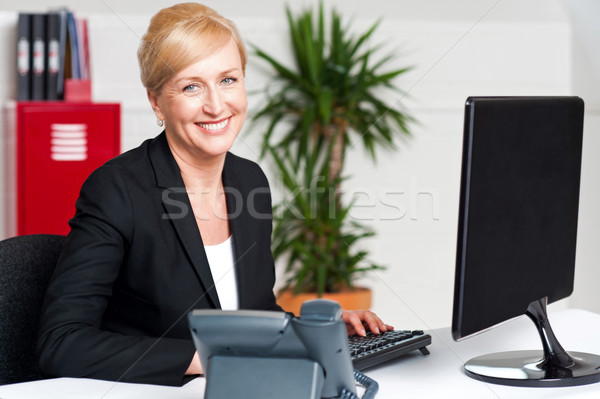 Smiling corporate woman typing on keyboard Stock photo © stockyimages