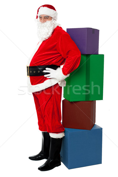 Santa leaning over colorful pile of Xmas presents Stock photo © stockyimages