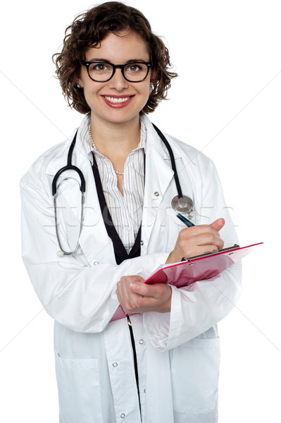 Smiling medical practitioner writing report Stock photo © stockyimages