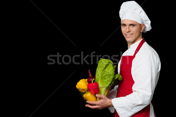 Handsome chef holding vegetables bowl Stock photo © stockyimages