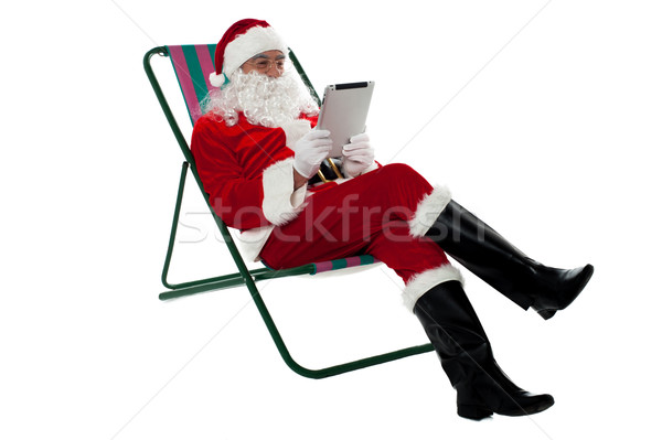 Kris Kringle relaxing and using electronic tablet Stock photo © stockyimages