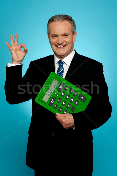 Confident executive holding calculator and gesturing okay sign Stock photo © stockyimages