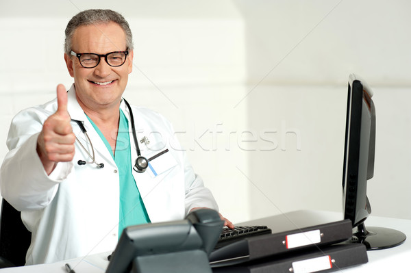 Mosolyog orvos gesztikulál remek kamerába dolgozik Stock fotó © stockyimages