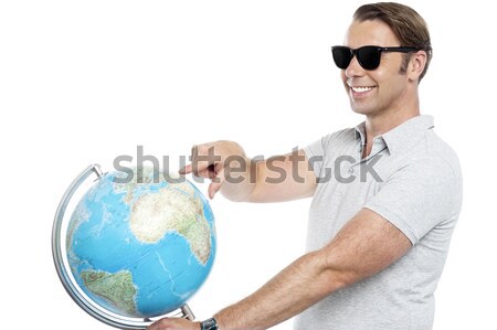 Man holding globe and pointing over it Stock photo © stockyimages