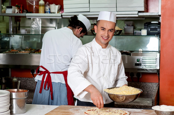 Stock photo: Young chef making pizza at kitchen