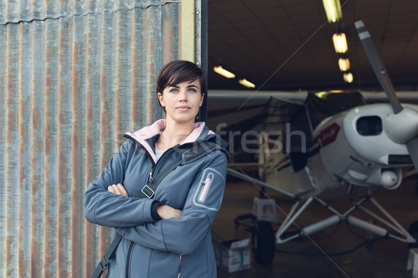 Smiling woman leaning against the hangar walls Stock photo © stokkete