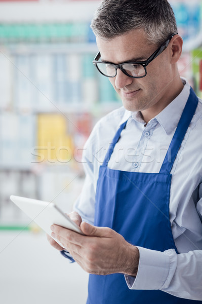 Supermarket clerk working with a tablet Stock photo © stokkete