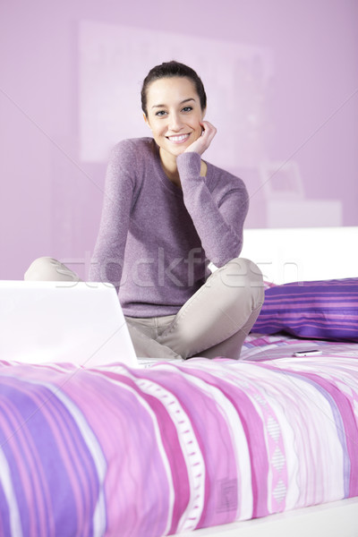 Portrait of a young female relaxing in bed while using laptop Stock photo © stokkete