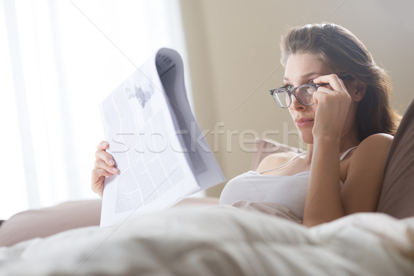 érdekes fiatal nő ágy otthon olvas újság Stock fotó © stokkete