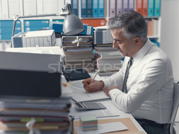 Businessman working in the office and piles of paperwork Stock photo © stokkete