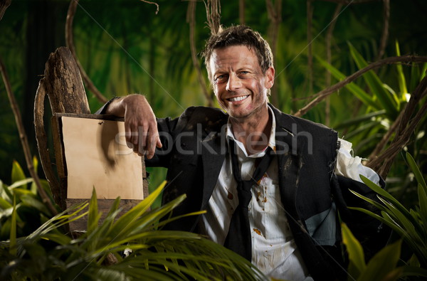 Survivor businessman leaning to a sign in the jungle Stock photo © stokkete