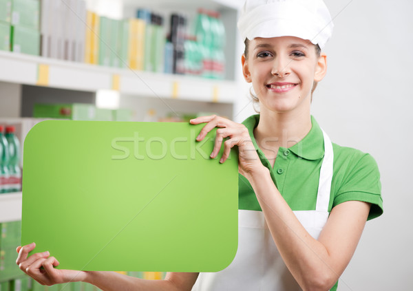 Female sales clerk with green sign Stock photo © stokkete