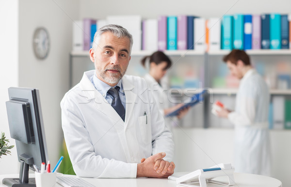 Arzt besetzt Schreibtisch schauen Kamera Gesundheitswesen Stock foto © stokkete