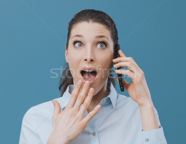 Shocked woman using a smartphone and connecting Stock photo © stokkete