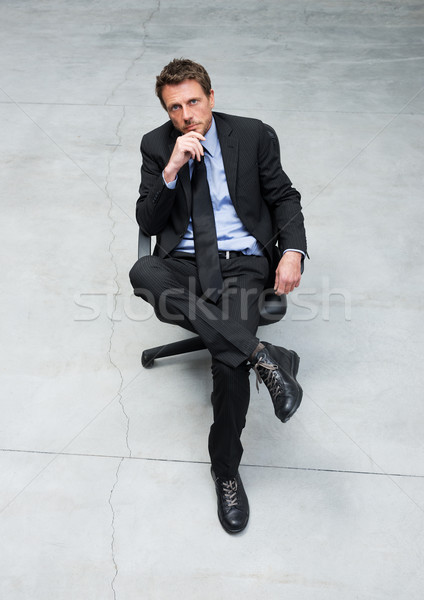Biznesmen posiedzenia krzesło biurowe uśmiechnięty strony podbródek Zdjęcia stock © stokkete