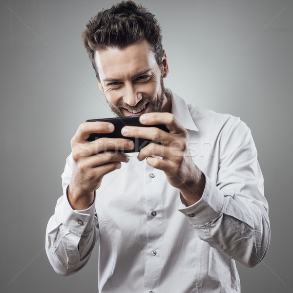 Jóképű férfi játszik okostelefon jóképű fiatalember internet Stock fotó © stokkete