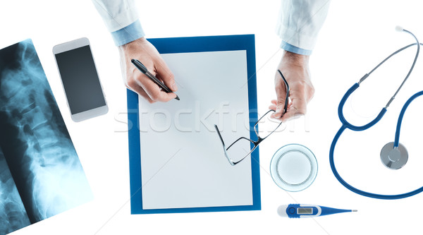 Doctor writing a prescription on a clipboard Stock photo © stokkete