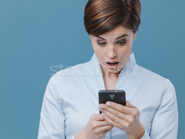 Woman receiving a surprise on her smartphone Stock photo © stokkete