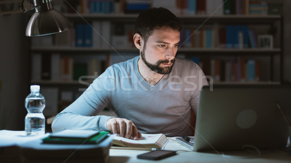 Pracy nadgodziny młody człowiek posiedzenia biurko za pomocą laptopa Zdjęcia stock © stokkete