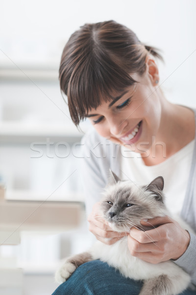 Mosolygó nő ölelkezés macska mosolyog fiatal nő tart Stock fotó © stokkete