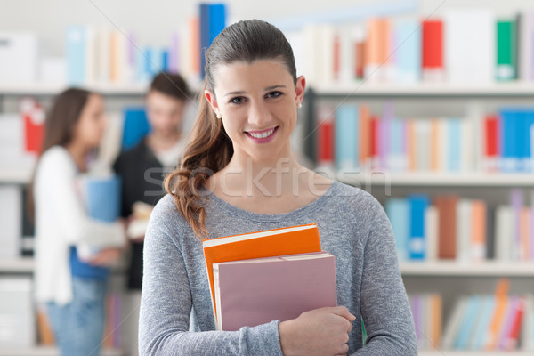 [[stock_photo]]: étudiant · posant · bibliothèque · souriant · fille