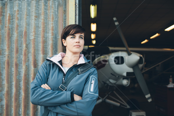 Smiling woman leaning against the hangar walls Stock photo © stokkete