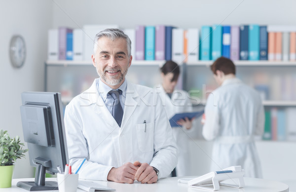 Arzt besetzt Schreibtisch lächelnd medizinischen Personal Stock foto © stokkete