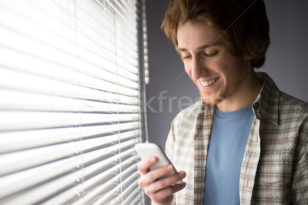 Stock foto: Smartphone · junger · Mann · lächelnd · Fenster · Technologie