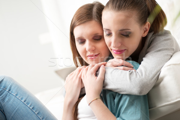 Girlfriends hugging on sofa Stock photo © stokkete