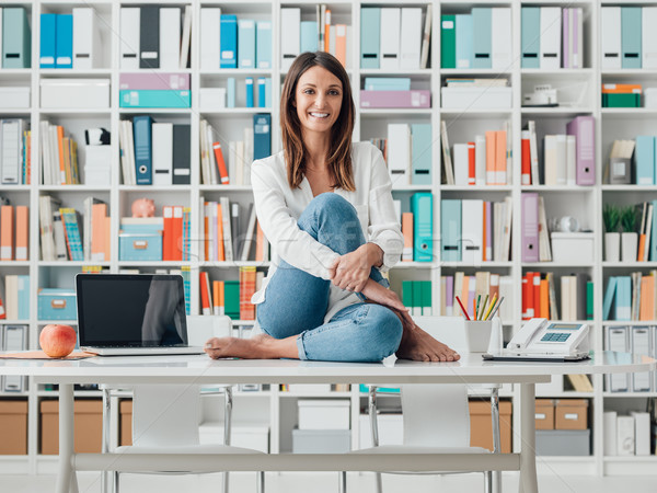 Smiling woman sitting on the top of the desk Stock photo © stokkete