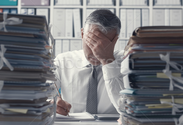 Stressed business executive and piles of paperwork Stock photo © stokkete