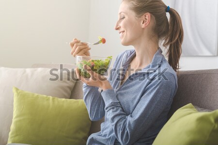 Mulher jovem alimentação salada sessão geladeira cozinha Foto stock © stokkete