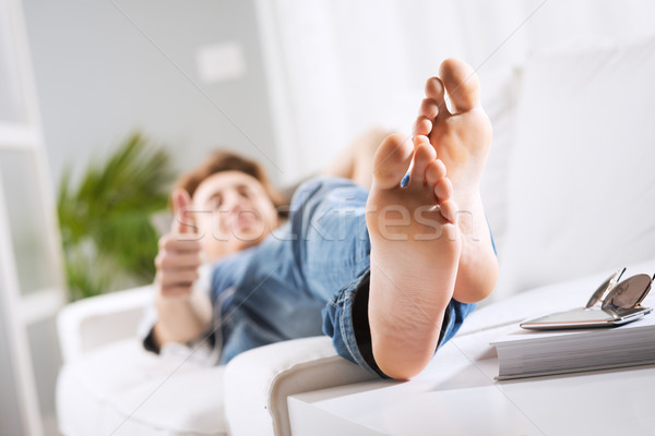Megnyugtató mezítláb fiatalember kanapé nappali közelkép Stock fotó © stokkete