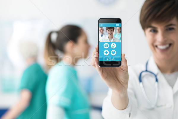 Female doctor holding a smartphone Stock photo © stokkete