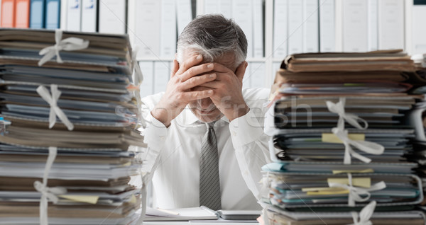 Stressed business executive and piles of paperwork Stock photo © stokkete