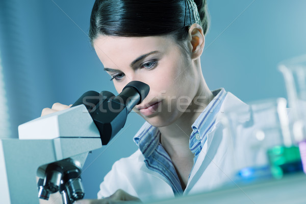 Stock photo: Female researcher using microscope